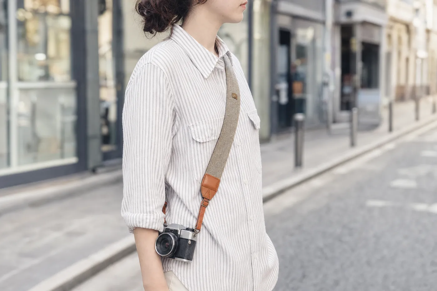 A photographer walking with a camera hanging across the body on a strap