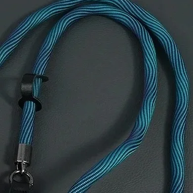 Teal marled braided rope camera strap coiled, showing the two-tone nylon braid and metal end fitting